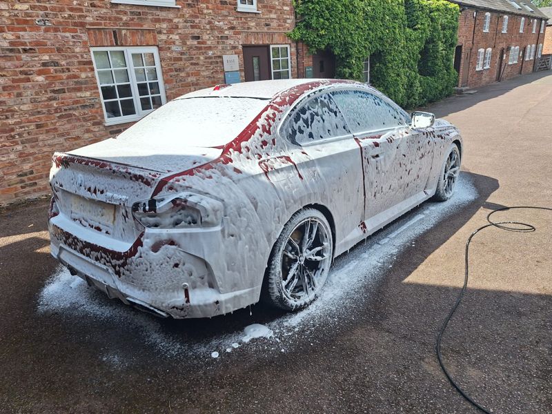 A car covered in snow foam before its hand wash