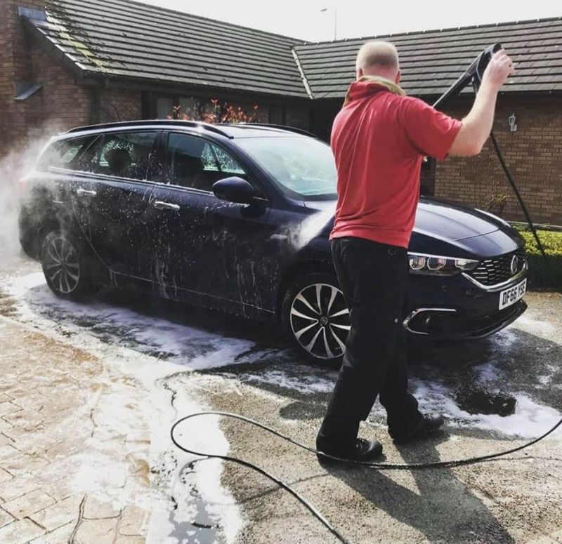 Barry pressure washing a car on a client's driveway